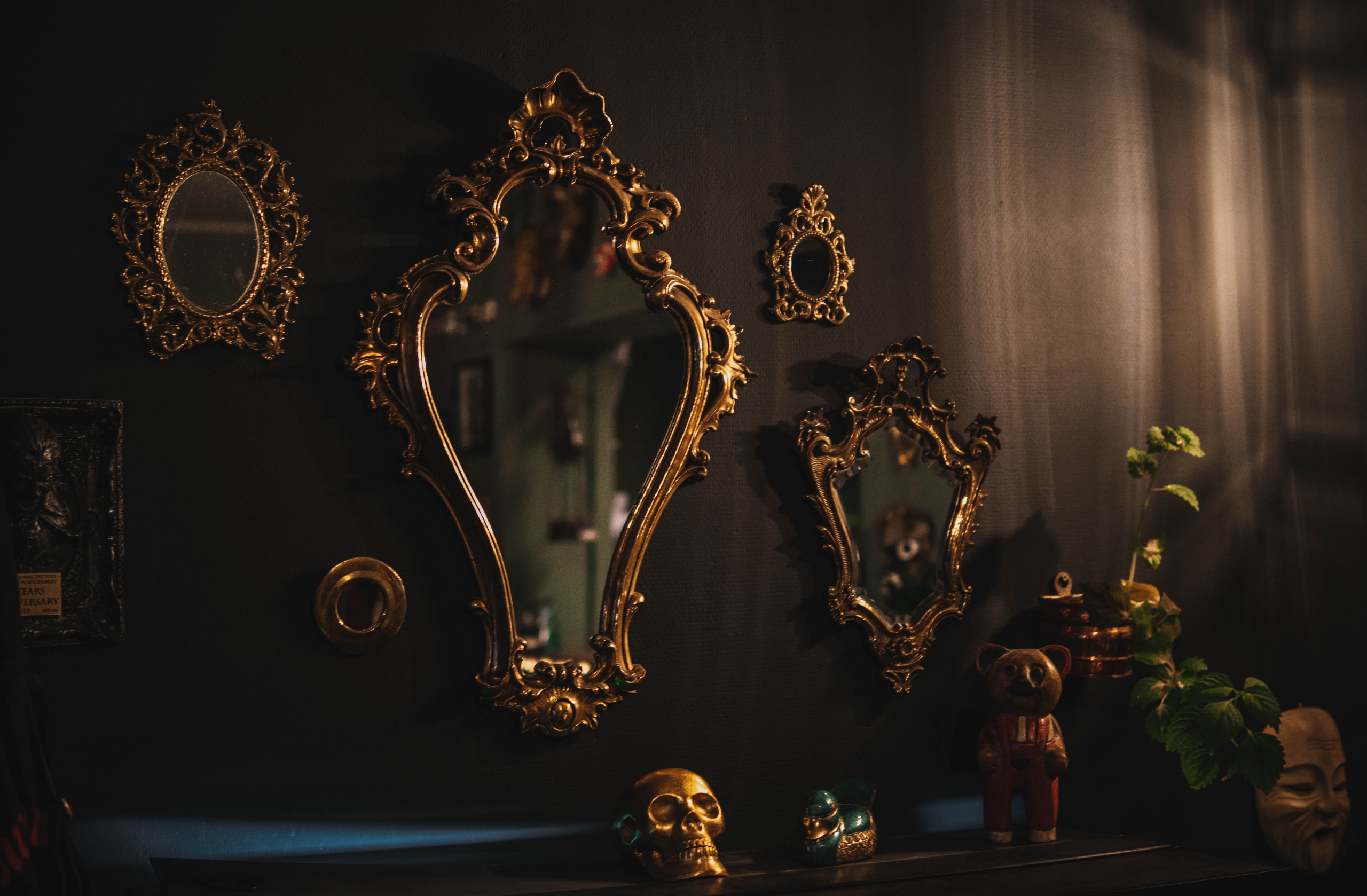 Ornate gold gilt mirrors on a wall surrounded by antique items