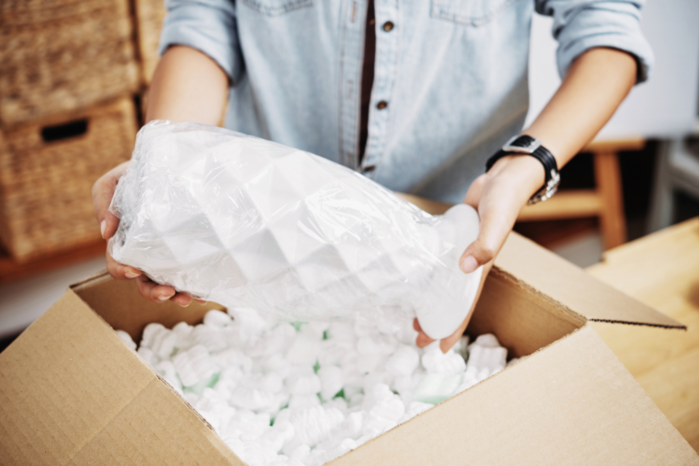 Closeup of hands loading a fragile vase into a box