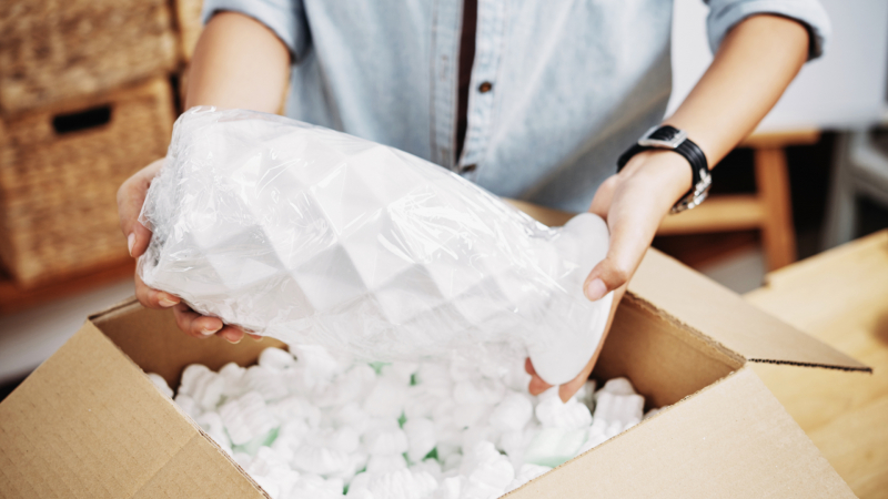 Closeup of hands loading a fragile vase into a box