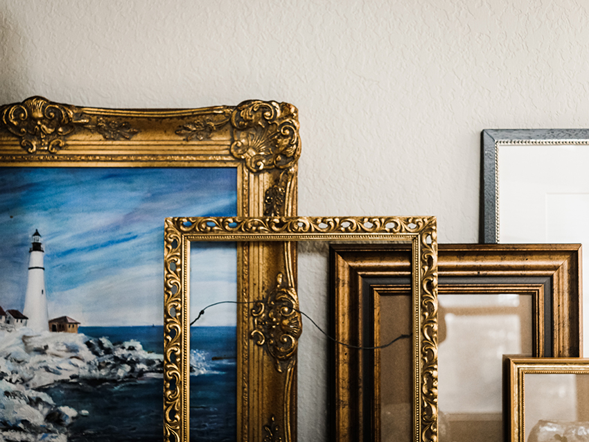 Gold frames stacked in front of a wall