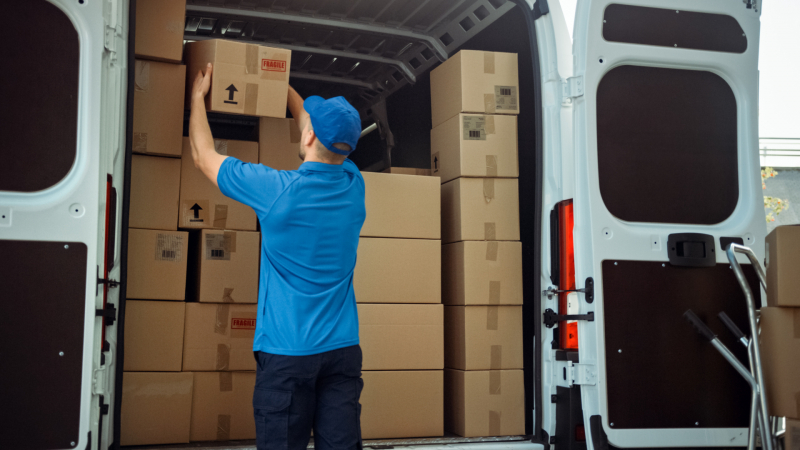 Delivery driver taking a fragile box out the back of a van.