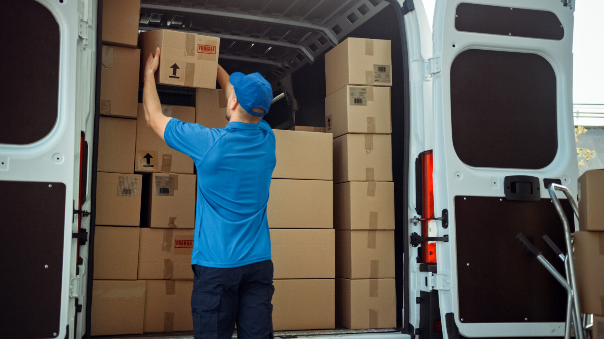 Delivery driver taking a fragile box out the back of a van.