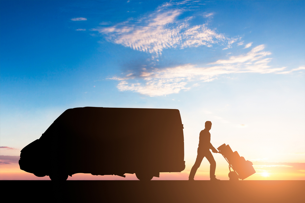 Silhouette Of Delivery Courier With Cardboard Boxes On Trolley