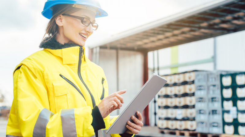 Female wearing a safety helmet and checking a tablet,